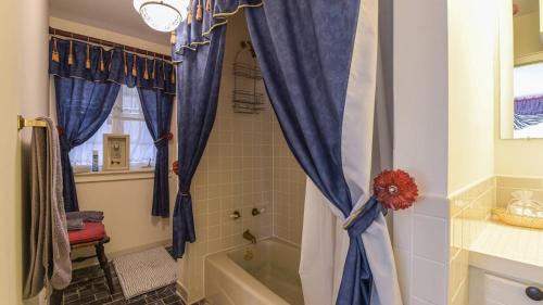 a bathroom with a shower with blue curtains and a tub at Hamersmith Hollow Retreat by AvantStay Mountain Views in Mars Hill