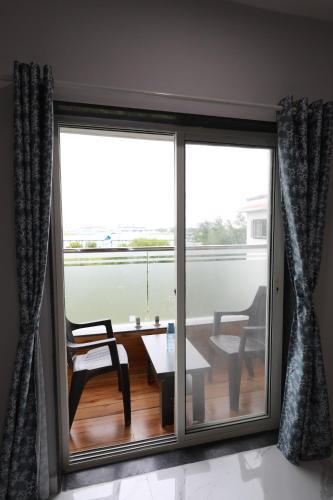 a sliding glass door with a table and a chair at Azura Vista by Alt Acco in Pune