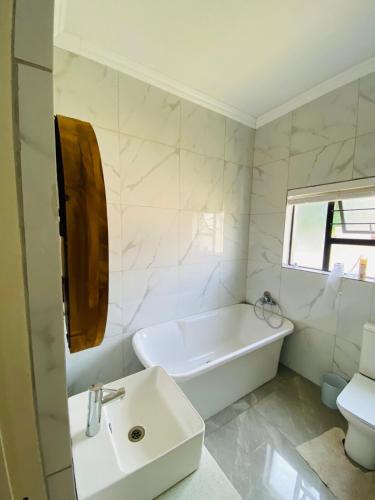 a white bathroom with a tub and a sink at Alimu villa in Nelspruit