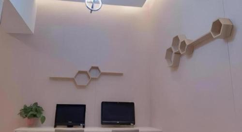 a room with two monitors on a wall at GreenTree Inn Luoyang Henan University of Science and Technology in Luoyang