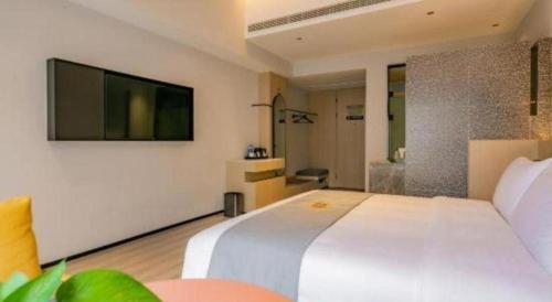 a bedroom with a large white bed and a television at Airfeel Hotel in Ziyang
