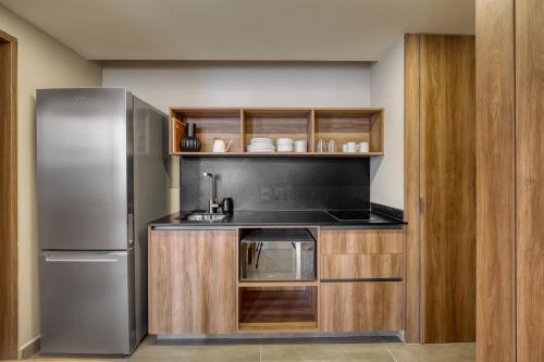 a kitchen with a stainless steel refrigerator and wooden cabinets at Namóra by Lumina in Guadalajara