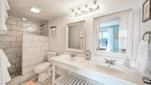 a white bathroom with a sink and a toilet at Beachfront Complex w 2 Pools Tennis Gulf Views Rise N Beach by AvantStay in Port Aransas