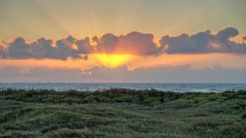 a sunset over the ocean with the sun setting at Beachfront Complex w 2 Pools Tennis Gulf Views Rise N Beach by AvantStay in Port Aransas