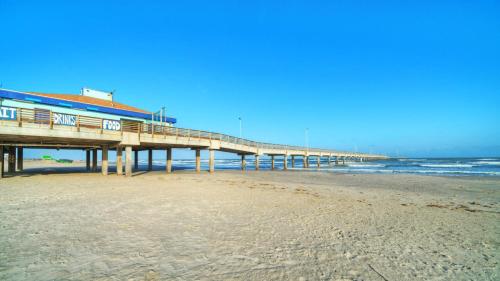 a pier on the beach next to the ocean at Beachfront Complex w 2 Pools Tennis Gulf Views Rise N Beach by AvantStay in Port Aransas