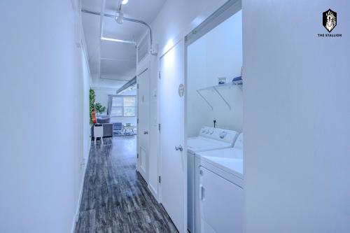a white bathroom with a sink and a hallway at The Stallion #305 - Walk to Attractions - Modern Spacious 1BD Loft in Memphis Downtown in Memphis