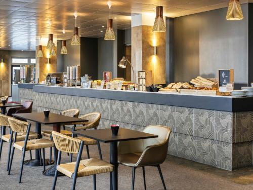 a restaurant with tables and chairs in front of a counter at ibis Paris porte de Bercy in Charenton-le-Pont