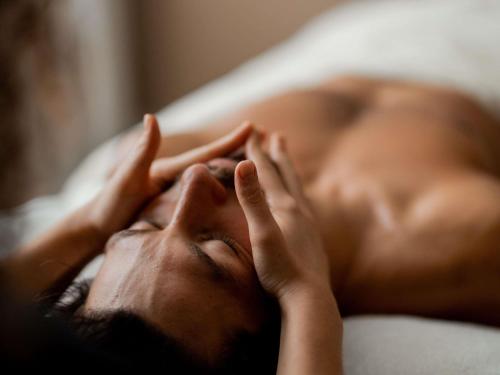 a man laying on a bed with his hands on his face at Sofitel Biarritz Le Miramar Thalassa in Biarritz
