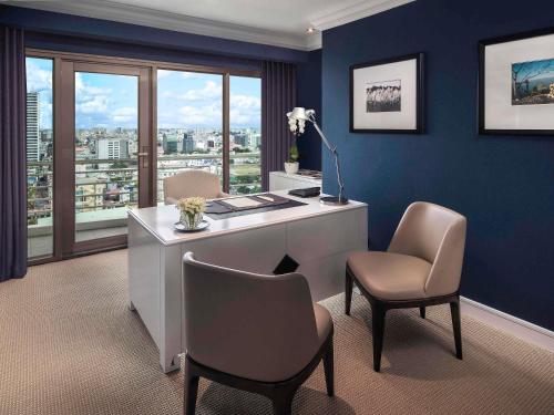 a office with a desk and two chairs and a window at Sofitel Saigon Plaza in Ho Chi Minh City