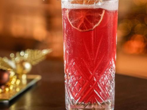 a glass of red drink with an orange slice in it at Sofitel Biarritz Le Miramar Thalassa in Biarritz