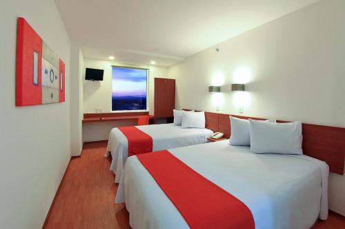 a hotel room with two beds and a window at One Queretaro Aeropuerto in Querétaro