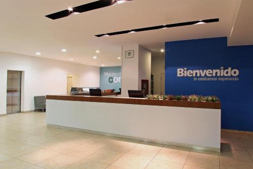 an office lobby with a reception counter and a blue wall at One Queretaro Aeropuerto in Querétaro