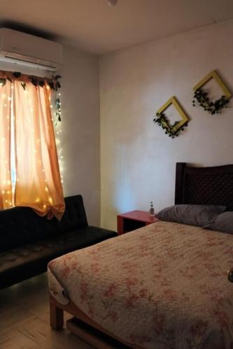 a bedroom with a bed and a couch and a window at Casa Ambar 2 recamaras,aire acondicionado y factura in Nogueras