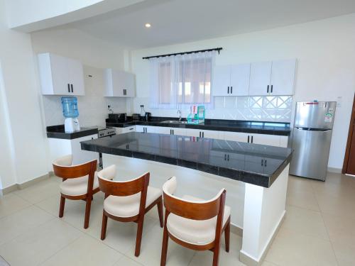a kitchen with a large island with chairs and a refrigerator at Baobab Waves in Mombasa
