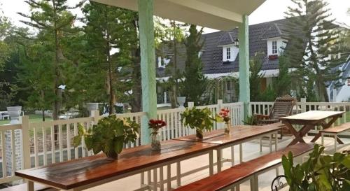 a porch with a wooden table with flowers on it at Charisma Resort in Ratchaburi
