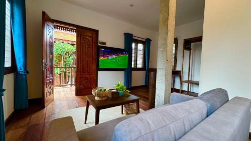 a living room with a couch and a tv at Sala Khmer - Traditional Wooden House & Garden in Siem Reap