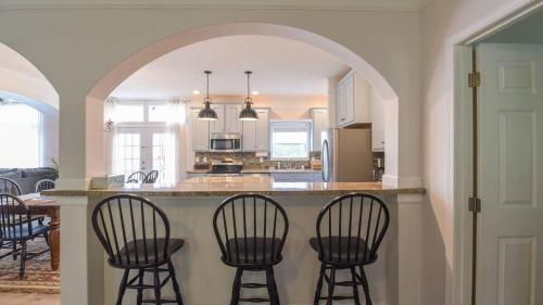 a kitchen with a island with four bar chairs at Riverside Ranch by AvantStay Mins to Downtown in Arden