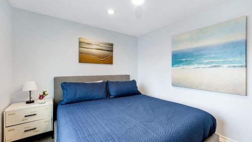 a bedroom with a blue bed and a painting on the wall at Shelly by AvantStay Steps to the Beach Deck w Ocean Views 5BDR in Newport Beach