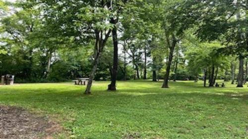 a park with trees and a picnic table in the grass at Riverside Ranch by AvantStay Mins to Downtown in Arden