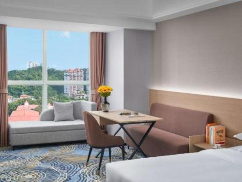 a hotel room with a bed and a table and a couch at Grand Nest Hotel (Tang Jia Wan Beach) in Zhuhai