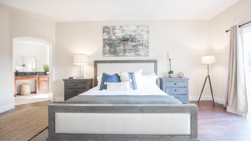 a white bedroom with a large bed with blue pillows at Grapevine by AvantStay Secluded 5BR Villa 4 Acres of Vineyards Avo Groves in Temecula