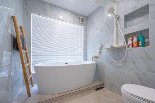 a bathroom with a tub and a toilet and a window at Coco Golf Villa in Ban Huai Luk (1)
