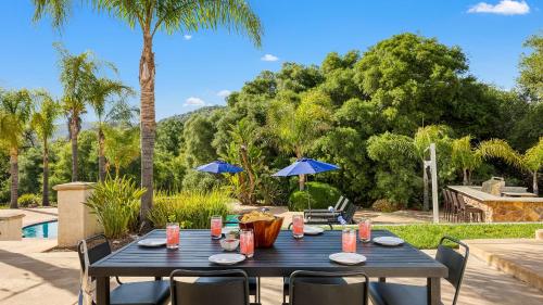 a black table with chairs and an umbrella at Grapevine by AvantStay Secluded 5BR Villa 4 Acres of Vineyards Avo Groves in Temecula
