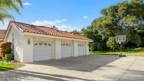 a house with two garage doors and a basketball hoop at Grapevine by AvantStay Secluded 5BR Villa 4 Acres of Vineyards Avo Groves in Temecula