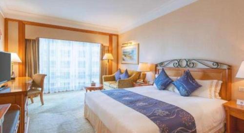 a hotel room with a large bed and a desk at Regency Hotel in Shantou