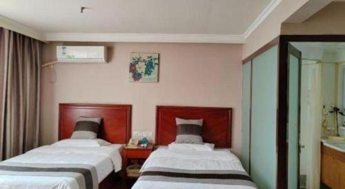 a hotel room with two beds and a mirror at GreenTree Inn Luoyang Zhongzheng Street Express Hotel in Luoyang