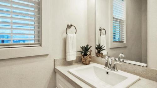 un bagno bianco con lavandino e specchio di Newly Built Pool Walk to Old Town EatsMarina Shorely Goodness by AvantStay a Port Aransas