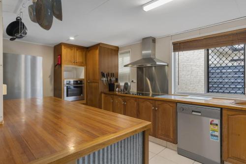 a kitchen with wooden cabinets and a wooden counter top at Bongaree Beach House with Pool in Bongaree