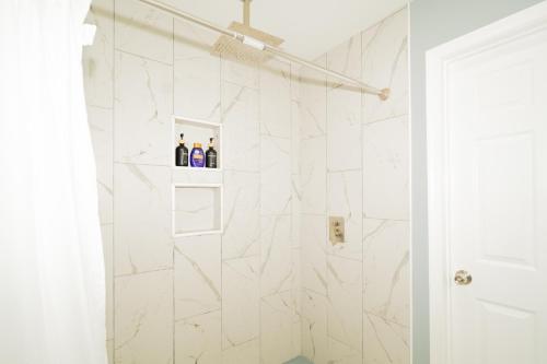 a bathroom with a shower with white tiles at Downtown upper canton 3 bdrm 3 bath home with rooftop and parking pad in Baltimore