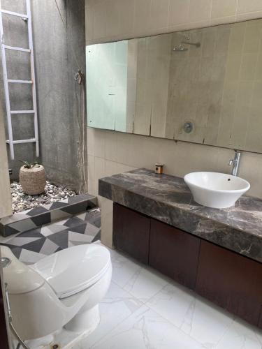 a bathroom with a white toilet and a sink at Mai Villa Umalas in Canggu