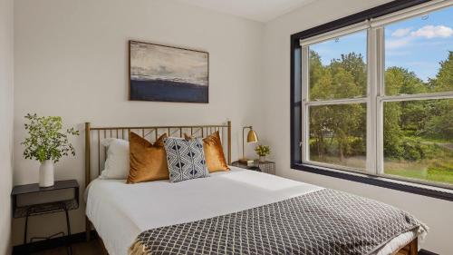 a bedroom with a bed and two large windows at For Lake Sake by AvantStay Lakefront Hot Tub View in Long Pond