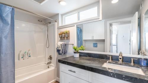 a bathroom with a sink and a shower and a tub at Ocean Breeze II by AvantStay Steps to the Beach in Newport Beach