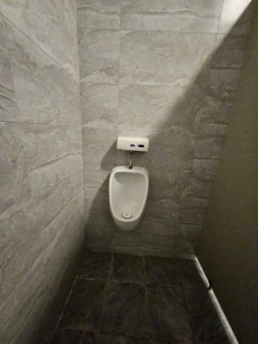 a bathroom with a urinal in a tiled wall at Blue Mountain Inn in Jinning