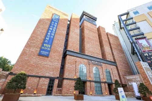 a large brick building with a blue sign on it at Cheongju Maryjane Hotel in Cheongju