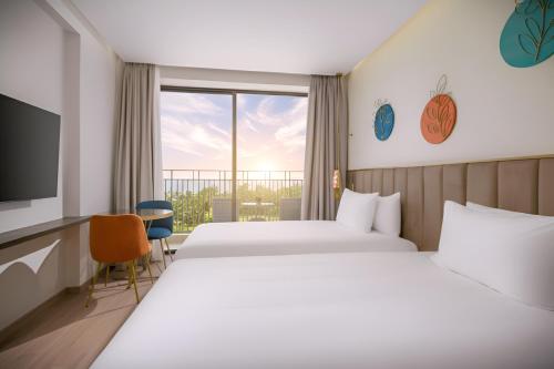 a hotel room with two beds and a television at Wyndham Hoi An Royal Beachfront Resort & Villas in Hoi An