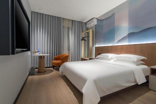 ein Schlafzimmer mit einem großen weißen Bett und einem Fernseher in der Unterkunft Jinjiang Inn Wenzhou Shuangyu The Terminal in Wenzhou