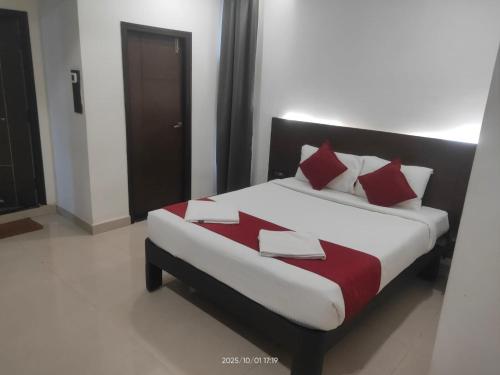 a bed with red and white pillows in a room at Hotel Orion Inn in Tirupati