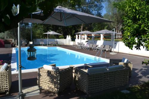 a swimming pool with chairs and an umbrella at Agriturismo Malena in Rossano