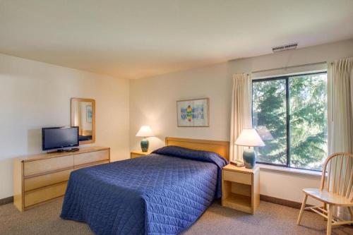 une chambre avec un lit bleu et une fenêtre dans l'établissement Wapato Point Resort, à Manson