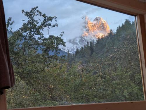 a window with a view of a fire in a forest at Ecohouse Svaneti in Mestia