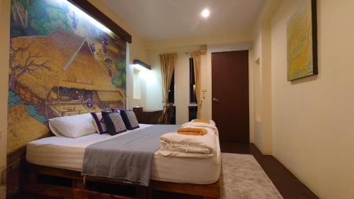 a bedroom with a bed with a large painting on the wall at ComeOn Stay&Sleep in Chiang Rai