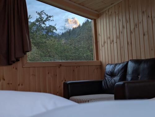 a room with a bed and a window with a couch at Ecohouse Svaneti in Mestia