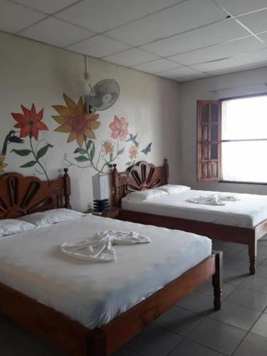 two beds in a room with flowers on the wall at El Mirador Ecológico, Ometepe in Altagracia