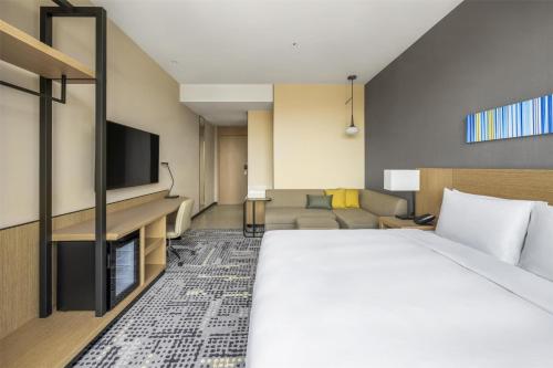 a hotel room with a bed and a flat screen tv at Hyatt Place New Taipei City Xinzhuang in Xinzhuang