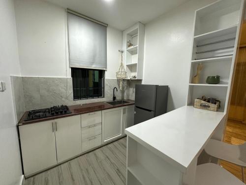 a kitchen with white cabinets and a black refrigerator at Dee s Home in Dar es Salaam