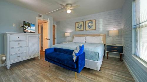 a bedroom with a blue bed and a blue chair at Beach Boardwalk Access Pool Remodeled Interior Tropical Haven by AvantStay in Port Aransas